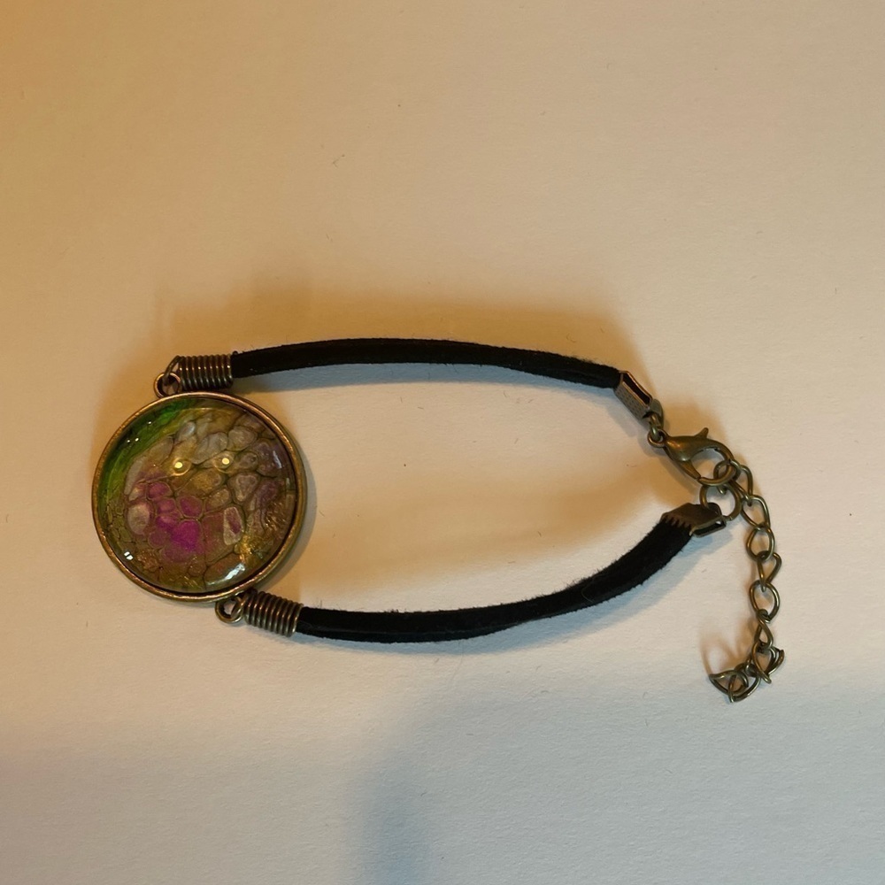 Hand painted acrylic design on glass bracelet.  Attached to metal.  Adjustable